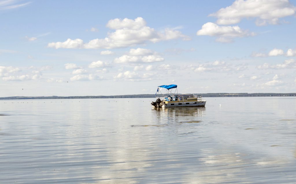 horizontal image of a pontoon boat coasting on a beautiful blue under clear blue sky in the summer time.