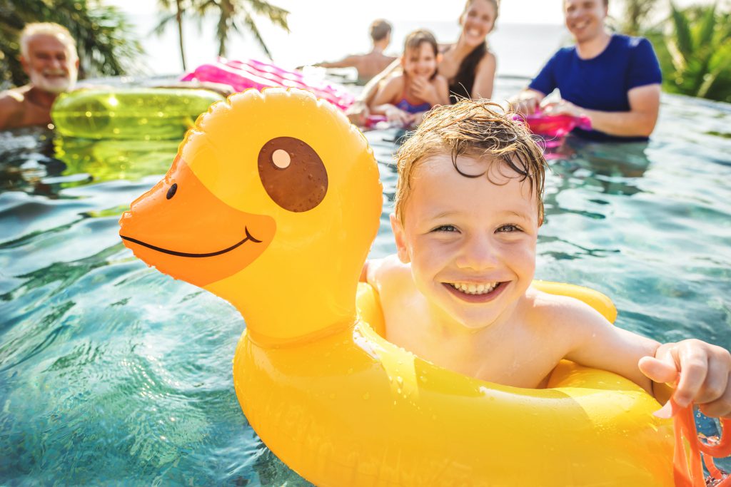 Boy swimming in a pool with family