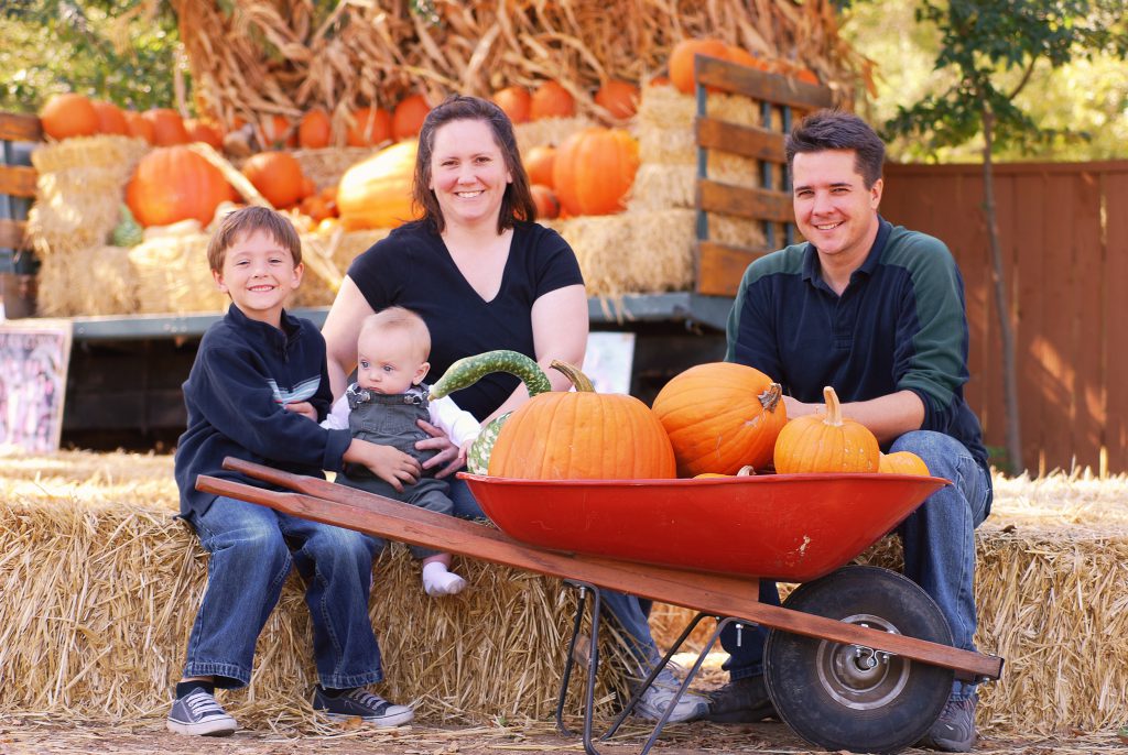 Portrait of a family of four at a pumpkin patch in autumn
