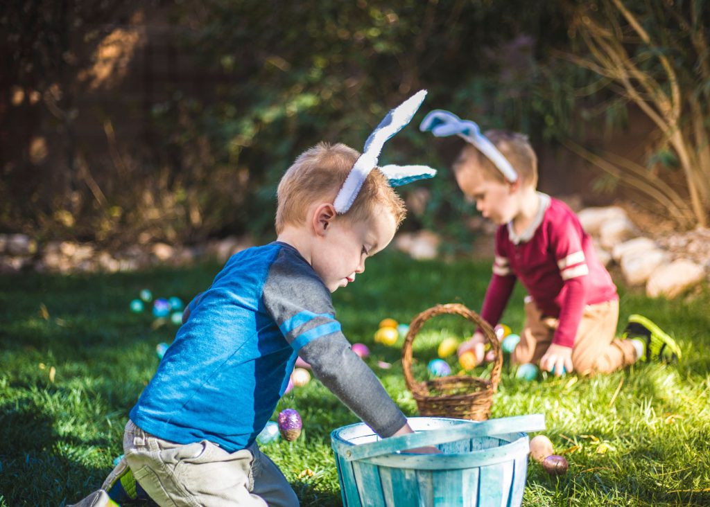 two young children picking up easter eggs and placing in their baskets on an Egg Hunt
