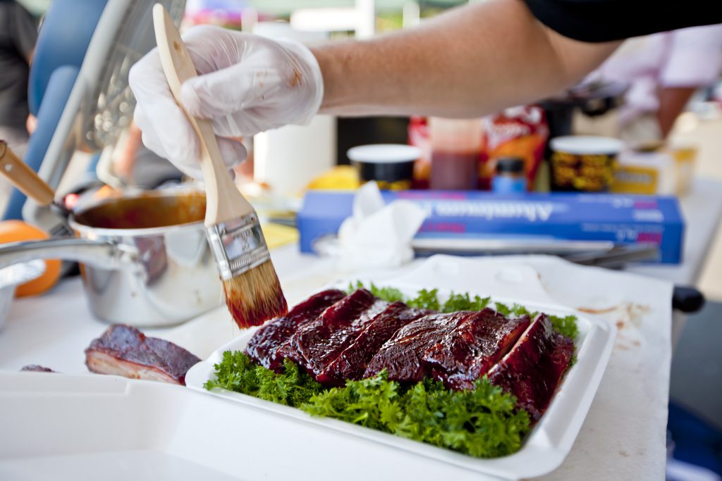 BBQ ribs being glazed in sauce as part of a competition