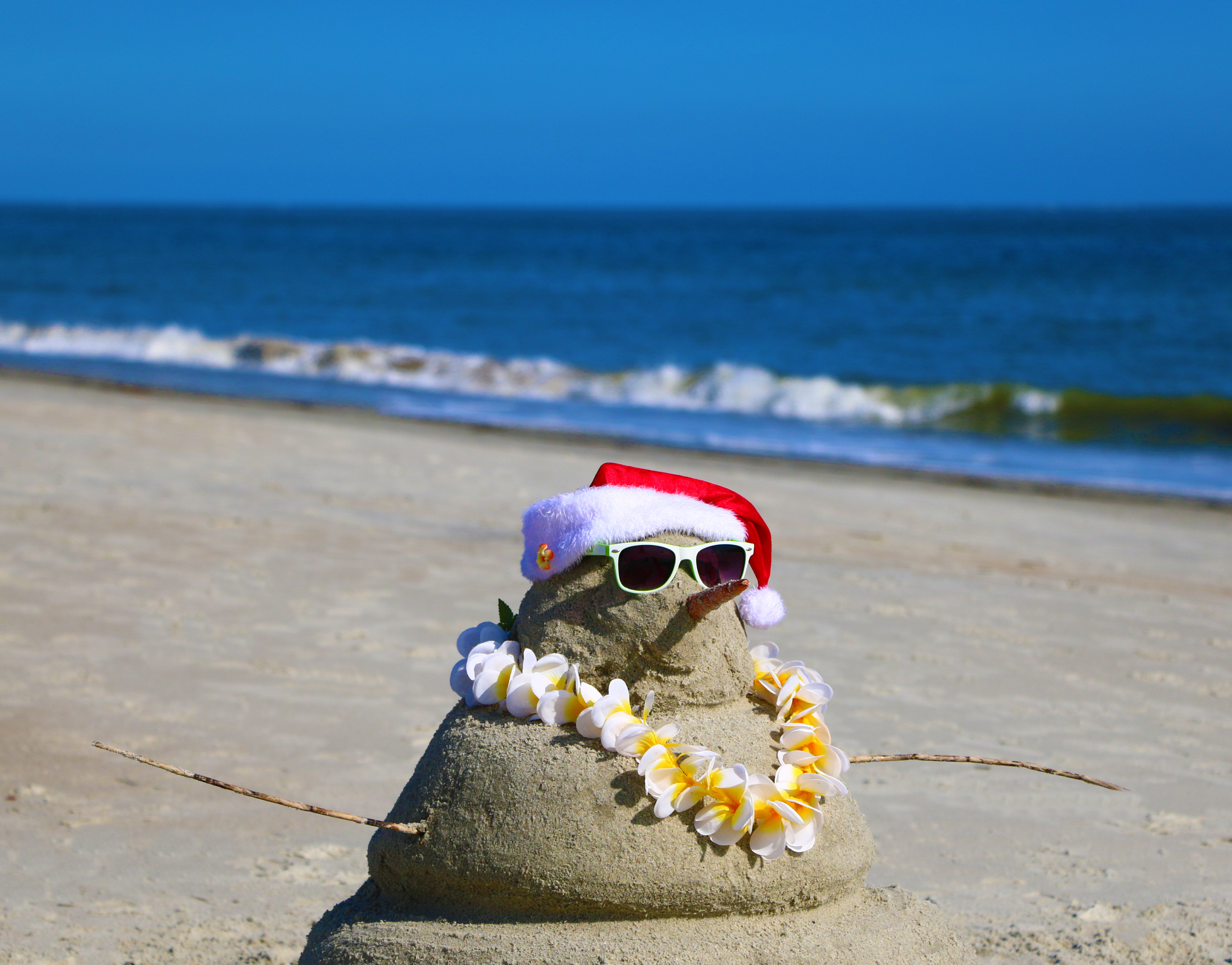 Snowman made of sand on a beach for a tropical Christmas holiday.