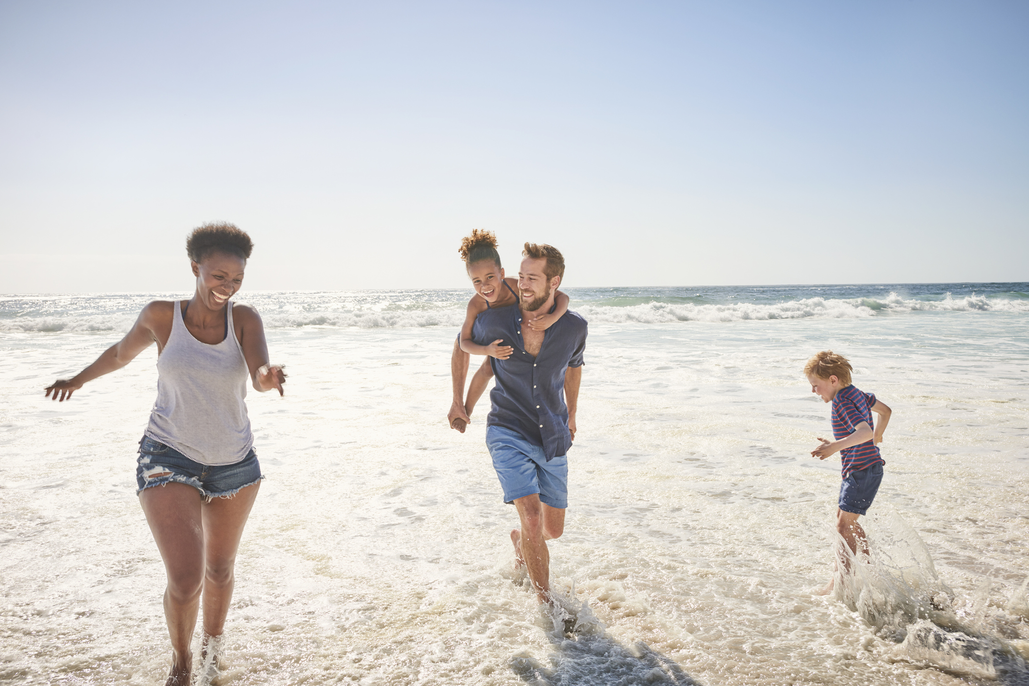 Family playing on beach, spring break, ocean waters, blue skies